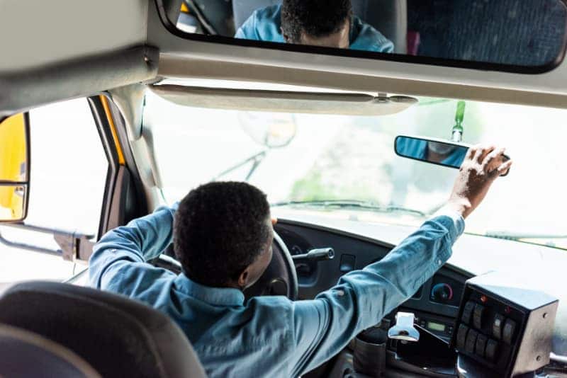 school bus driver checks mirror