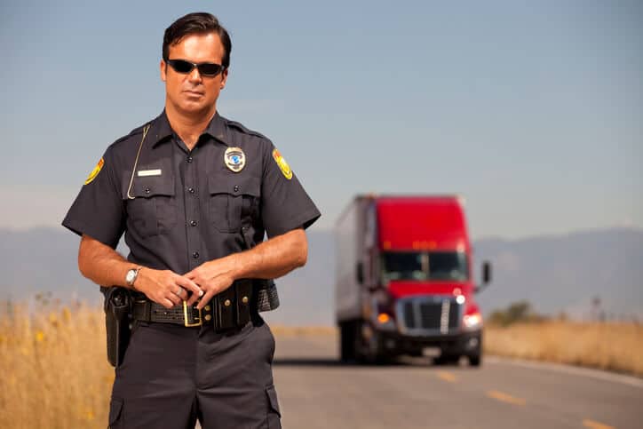 police officer in front of a red truck on a wide open road