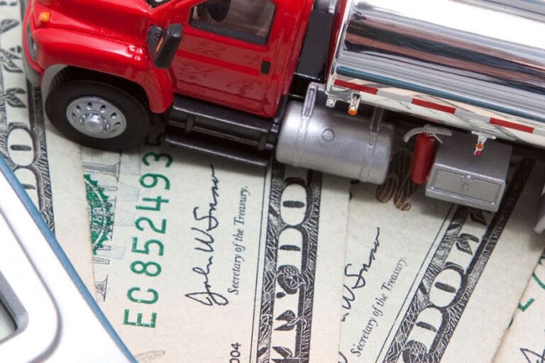 A toy truck sits on some dollars bills and a calculator