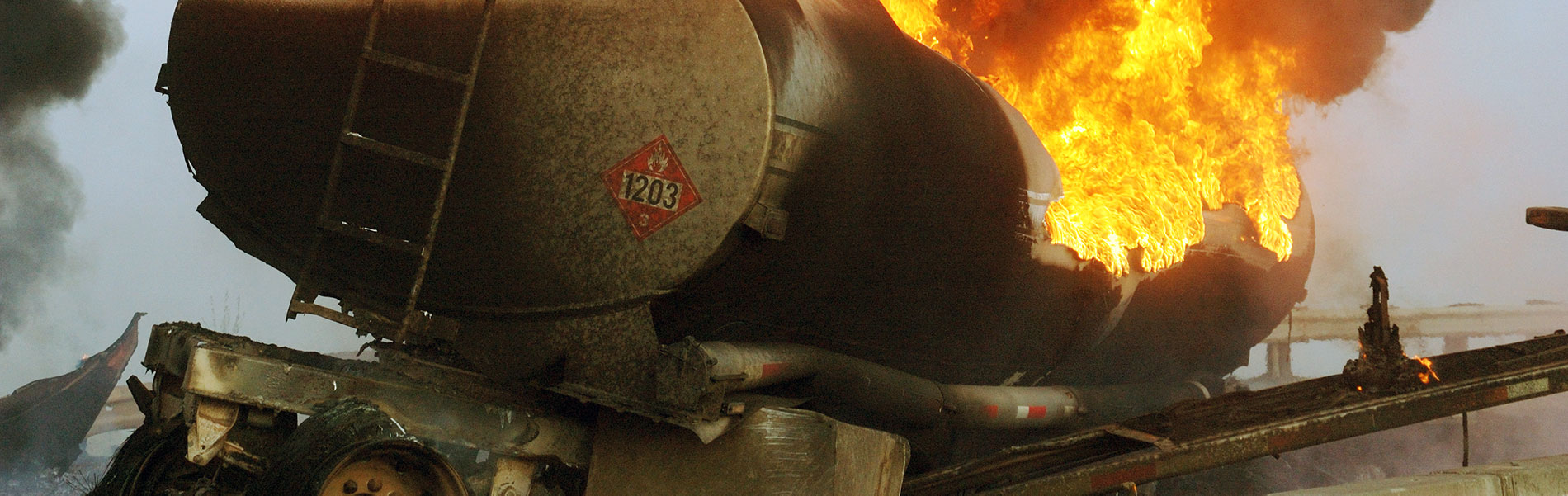 a tanker truck is on fire along side a highway with large flames jumping from it
