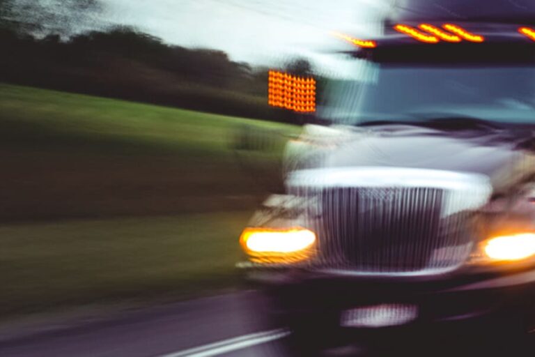 A white truck drives quickly down a highway road