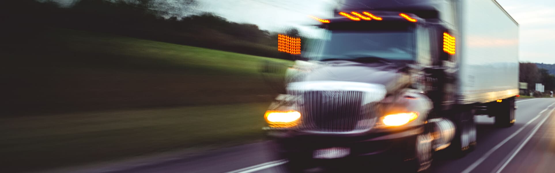 A white truck drives quickly down a highway road