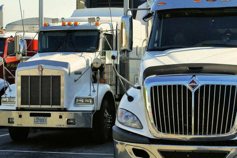 A row of semi-trucks sit in a parking lot