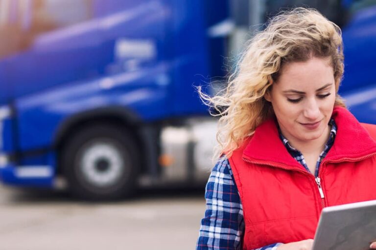 fleet management - A woman connects wirelessly to blue fleet trucks behind her