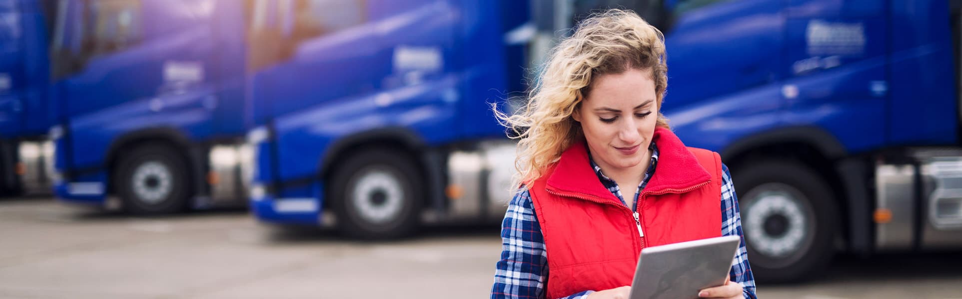 fleet management - A woman connects wirelessly to blue fleet trucks behind her