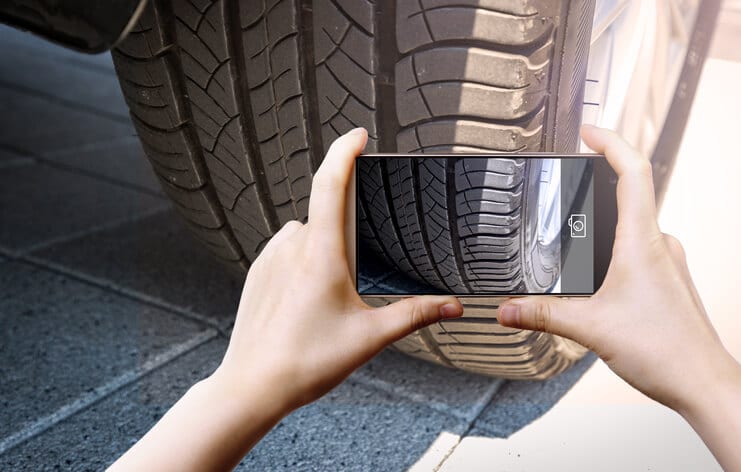 A fleet driver takes a photo of a tire with a cellphone camera for a DVIR - Government Fleet Management.