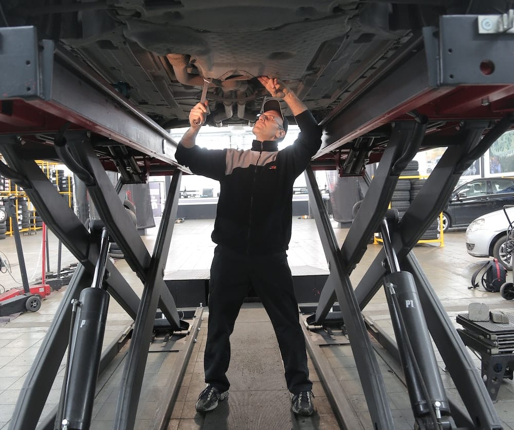 Man inspects the underside of a vehicle