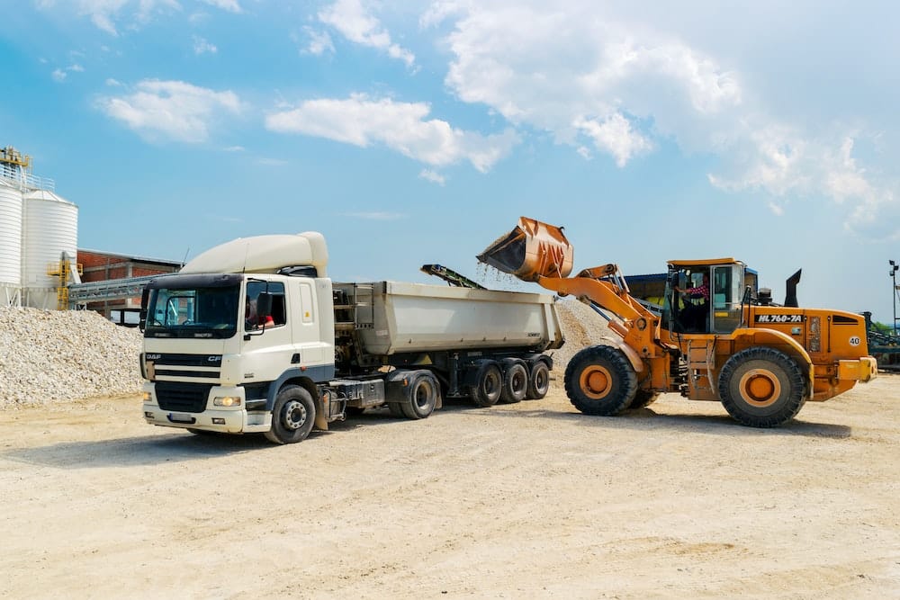 Tractor loading rock into a dump truck.