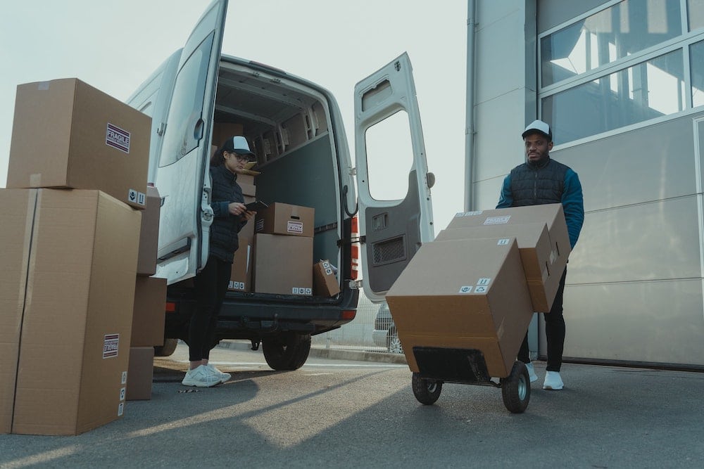 Worker unloading boxes from a van - small business vehicle tracking systems