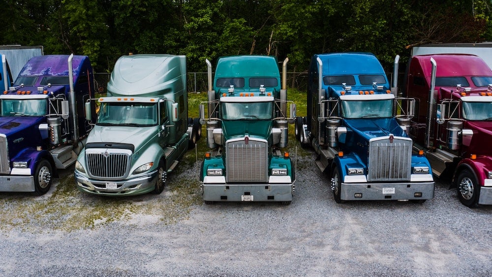 Several semi trucks parked beside eachother