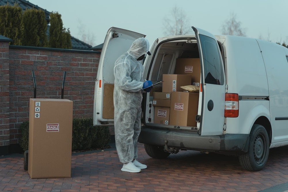 Delivery van driver in PPE inspecting van cargo