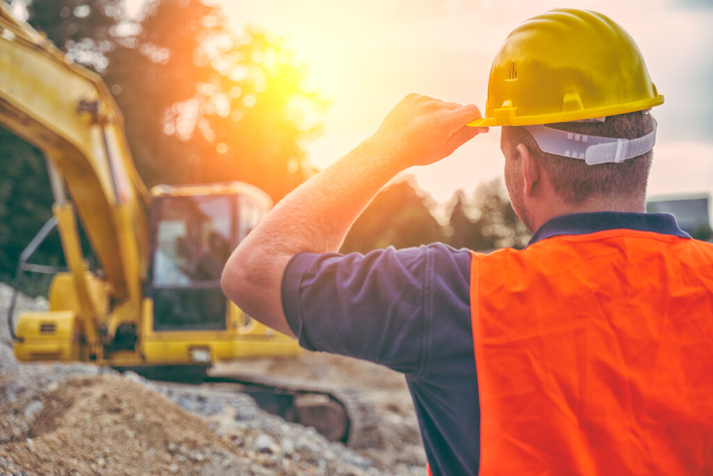 Construction worker wearing a hard hat in work areas and around equipment.