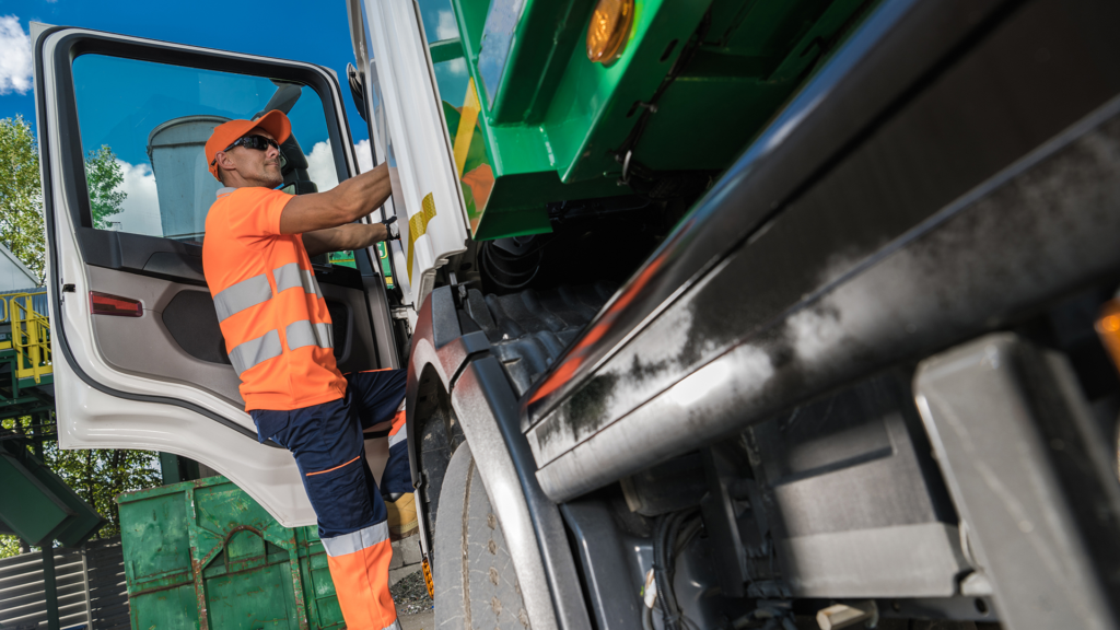 Driver climbing into a waste collection truck.