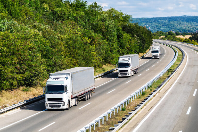 Three semi-trucks on a country road.