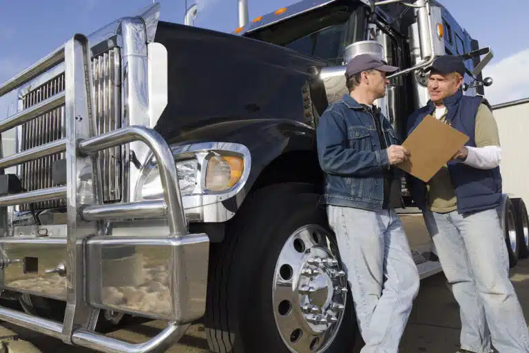 Two men talking in front of a semi-truck.