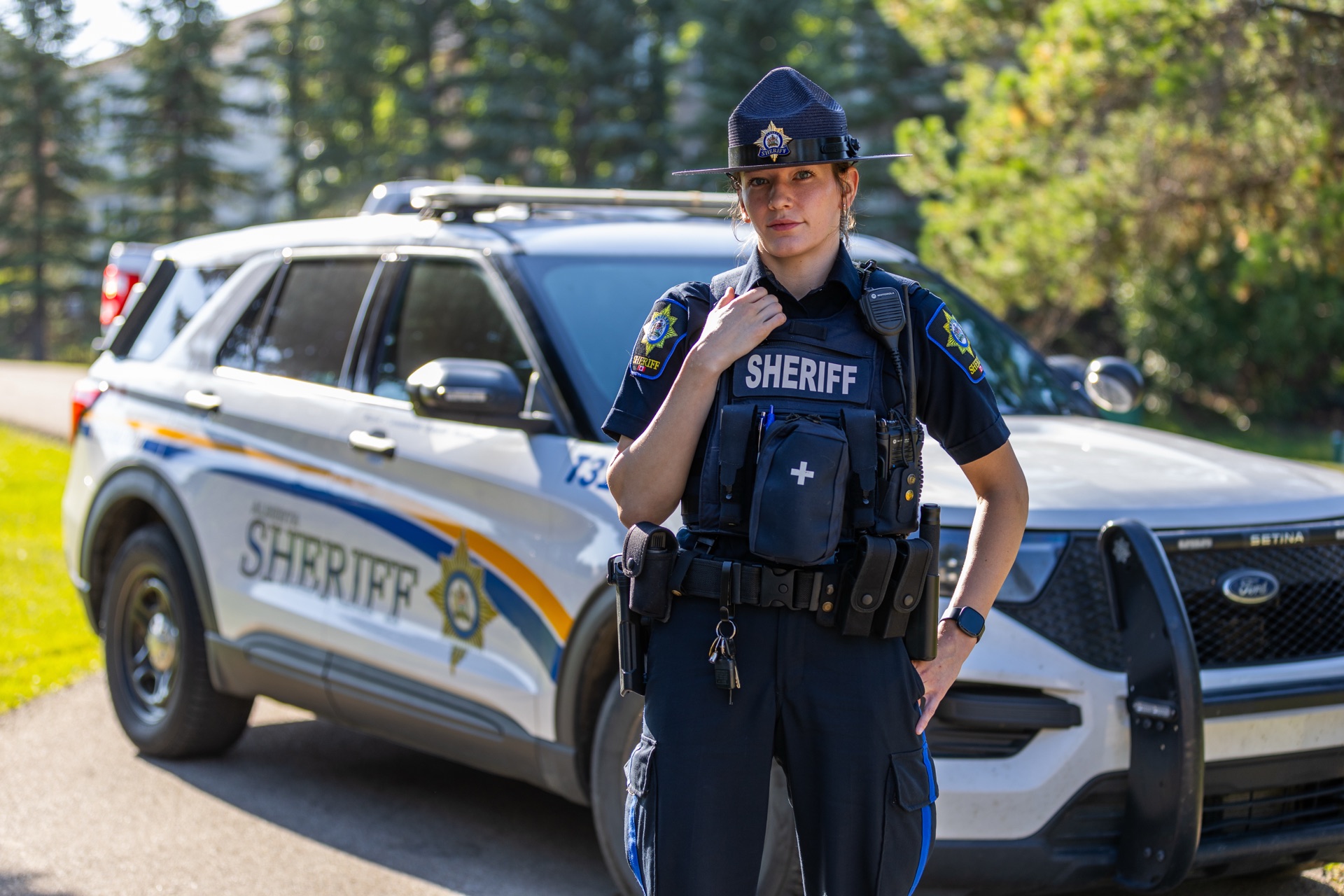 Oficial del sheriff de Alberta de pie frente a un vehículo de patrulla