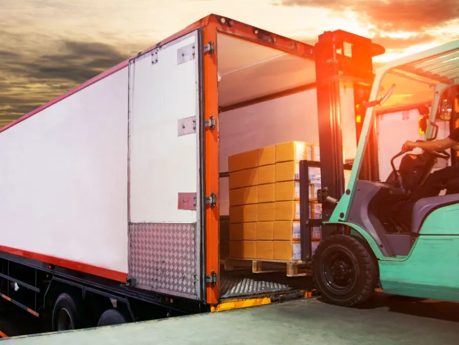 Forklift loading pallets into the open rear doors of a trailer