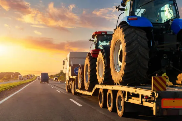 Low-loader trailer hauling tractors, seen from the side