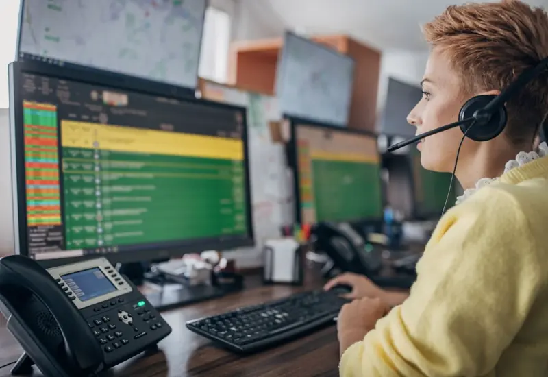 Dispatcher with a headset at monitors showing a live map